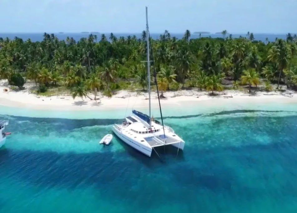 Lagoon 57 catamaran moored near a white-sand beach with palm trees in the San Blas Islands